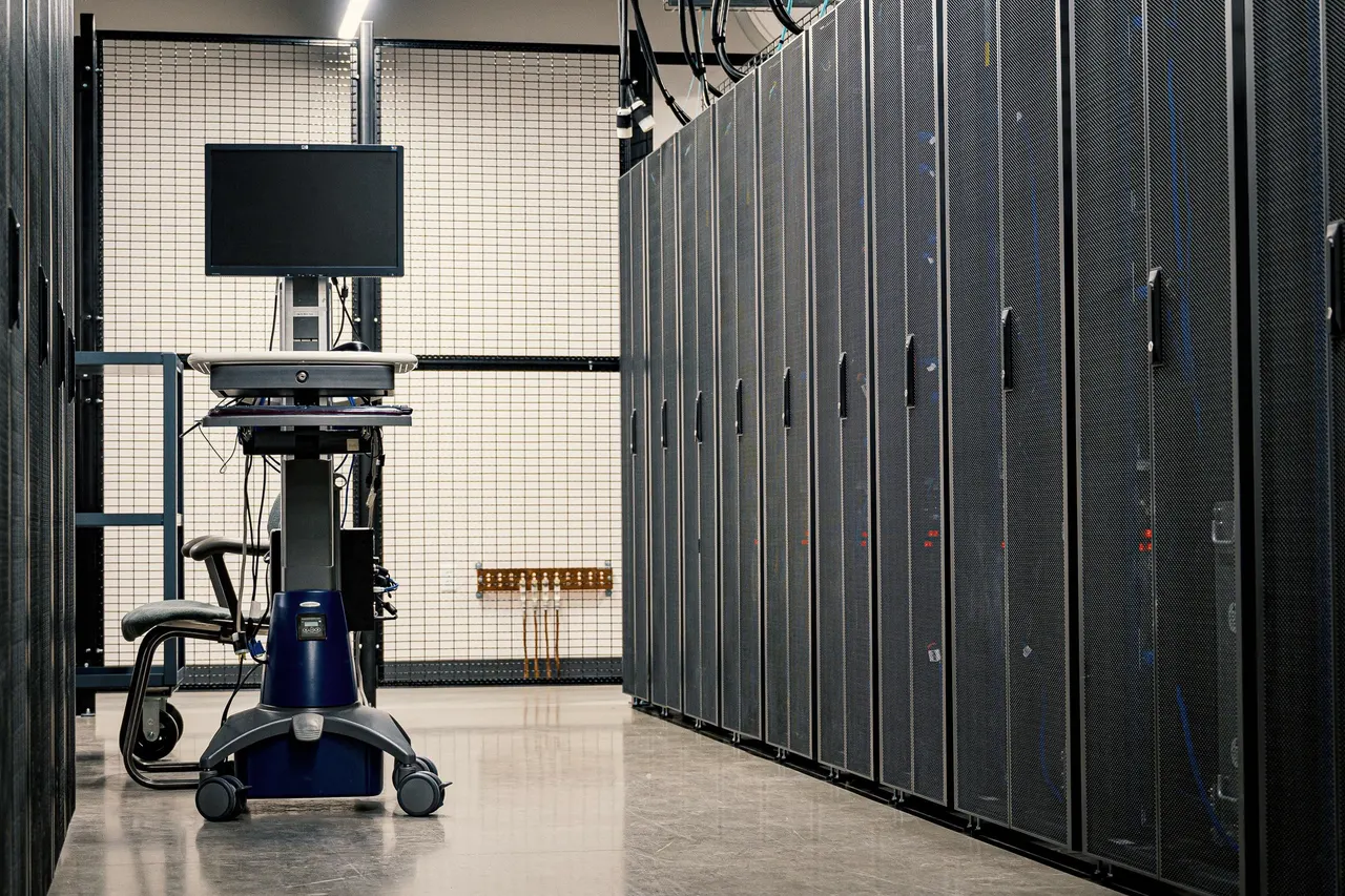 A row of closed black server cabinets along a data-hall aisle, with a monitor cart parked at the end