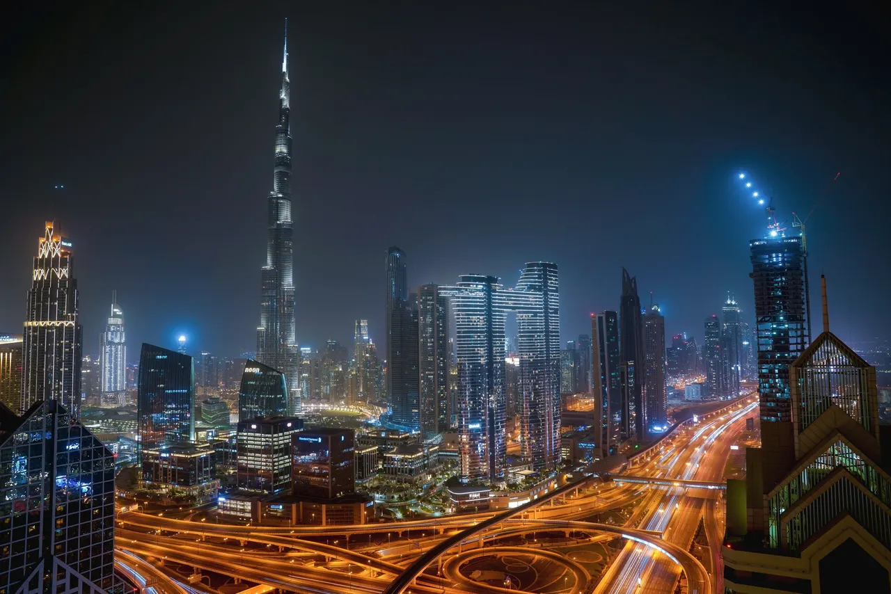 Dubai at night from above: the Burj Khalifa over lit towers and the light trails of Sheikh Zayed Road