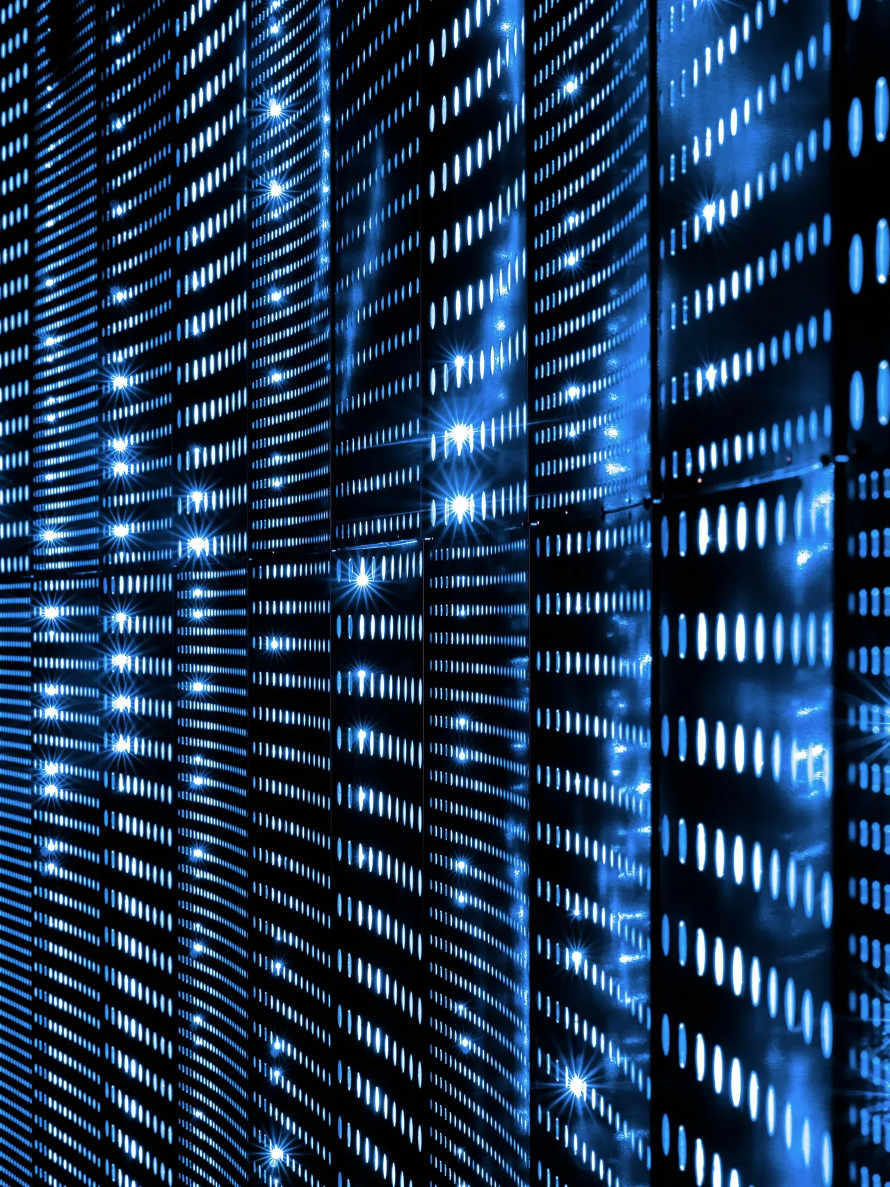 A wall of blue status LEDs on stacked equipment, receding into the dark